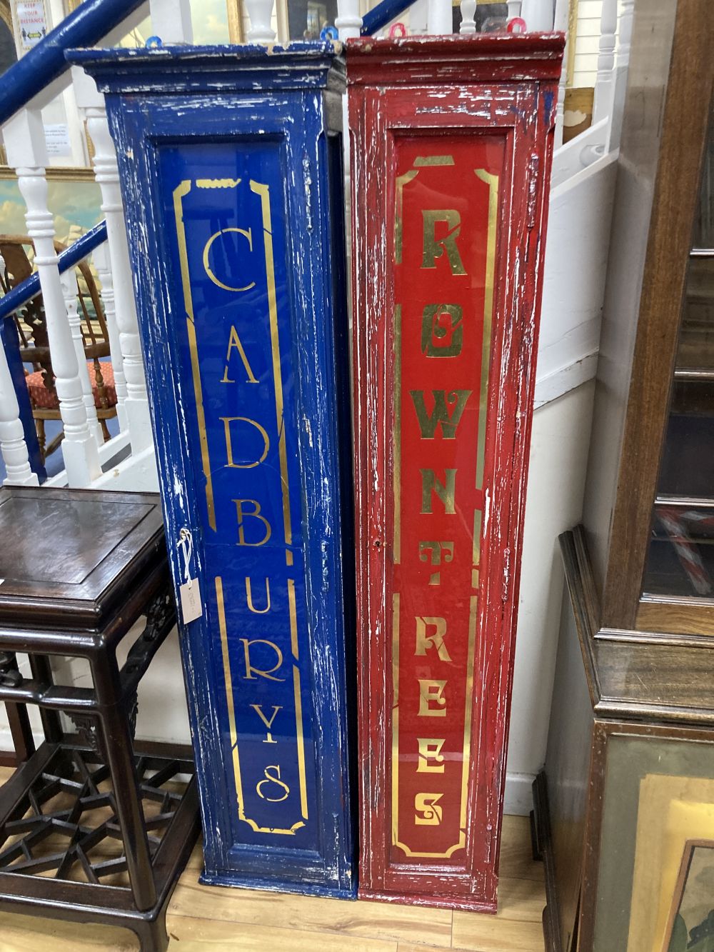 Two painted wood shop display cabinets, the glass doors marked Cadburys and Rowntrees, largest width 34cm height 140cm